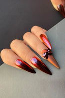 Obroi Nail art with red and gold metallic polish on a neutral background