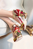 Obroi Decorative red and gold high-heeled shoes with floral details on a light background