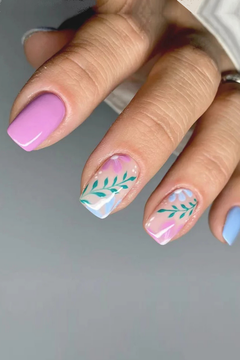 Nail art with pink and blue gradient and green leaf designs on a neutral background, Obroi