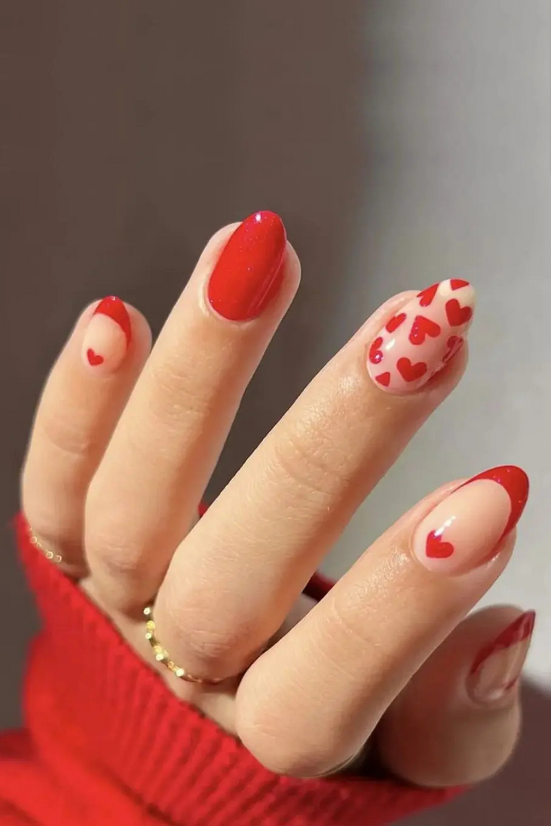 Obroi Hand with red nail polish and heart designs on a neutral background
