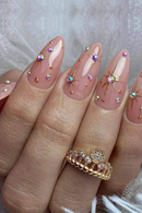 Nails with decorative gemstones and a gold ring on a neutral background, Obroi 