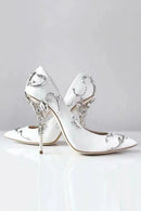 Pair of silver high-heeled shoes with decorative elements on a light gray background, Obroi
