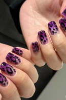 Close-up of hands with purple nail polish featuring a leopard print design, Obroi