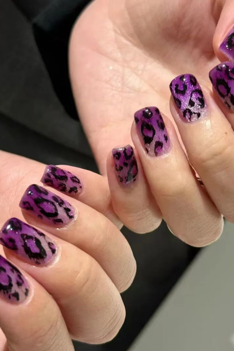 Close-up of hands with purple nail polish featuring a leopard print design, Obroi
