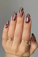 Hand with decorative nail art and gold rings on a gray background, Obroi