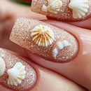 Close-up of a hand with almond-shaped nails decorated in a glittery champagne beige polish, featuring white and cream seashell designs, Obroi