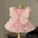 A pink children's dress displayed on a mannequin, featuring a large decorative butterfly back applique with pearl-like details, puff sleeves, and a layered tulle skirt with lace trim, Obroi