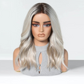 A long wavy wig with a silver-gray and dark brown ombré color, styled on a mannequin bust wearing a gray ribbed top against a clean white studio background, Obroi