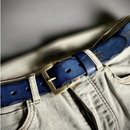 Close-up of a blue belt with a brass buckle on beige pants against a blurred background, Obroi