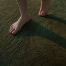 Close-up of feet standing on a textured green carpet, Obroi