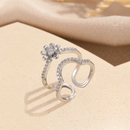 Silver open ring with floral design on a beige surface, Obroi