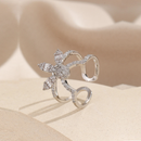 Silver bow-shaped ring with gemstones on a beige background, Obroi