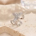 Silver ring with butterfly design on a beige stone surface, Obroi