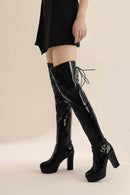 Black high-heeled boots worn with a black dress on a beige background, Obroi