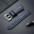 Blue leather watch strap with silver buckle on a dark surface with a pen, Obroi