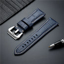 Blue leather watch strap with silver buckle on a dark surface with a pen, Obroi