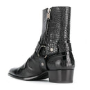 A black crocodile-embossed leather ankle boot with a side zipper, buckle strap detail, and a low block heel, shown from a three-quarters angle on a white background, Obroi