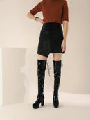 Person wearing a brown sweater, black skirt, and black knee-high boots on a neutral background, Obroi