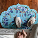 Person wearing fluffy slippers on a decorative rug with floral design on a wooden floor, Obroi