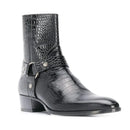 A black leather ankle boot with a crocodile-embossed pattern, featuring a side buckle strap with silver-tone hardware, a low block heel, and a pointed toe, shown against a plain white background, Obroi