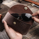 Brown leather sunglasses case with sunglasses on a wooden surface, Obroi