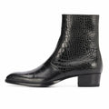 A black crocodile-embossed leather ankle boot with a low block heel and pointed toe, shown from a side profile on a white background, Obroi