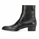 A black crocodile-embossed leather ankle boot with a low block heel and pointed toe, shown from a side profile on a white background, Obroi