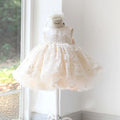 A sleeveless cream or ivory flower girl dress with a lace bodice and a full tulle skirt, displayed on a dress form mannequin in front of a bright window.