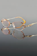 Pair of rimless eyeglasses on a reflective surface with a gray background, Obroi