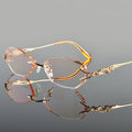 Pair of gold-rimmed eyeglasses on a reflective surface with a gray background, Obroi