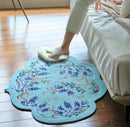 Decorative round rug with floral pattern on a wooden floor, person stepping onto it, Obroi