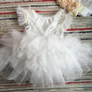 White lace baby dress with ruffles on a striped fabric background, Obroi