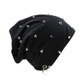 A black slouchy beanie hat decorated with multiple silver metal spikes and studs, featuring a silver metal grommet and ring at the bottom, shown on a plain white background, Obroi