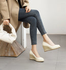 Person wearing blue jeans and beige wedge shoes, holding a white bag, Obroi