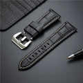 Black leather watch strap with silver buckle on a dark surface, Obroi