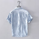 Light blue short-sleeve shirt on a hanger against a gray background, Obroi