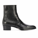 A black leather ankle boot with a crocodile-embossed texture, a low block heel, and a pointed toe, shown in profile against a white background, Obroi