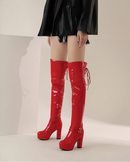 Red high-heeled boots worn with a black outfit on a neutral background, Obroi