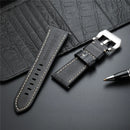Black leather watch strap with silver buckle on a dark textured surface, Obroi