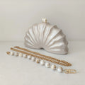 Shell-shaped clutch with a gold chain and pearl accents on a light background, Obroi