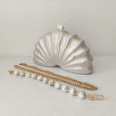 Shell-shaped clutch with a gold chain and pearl accents on a light background, Obroi