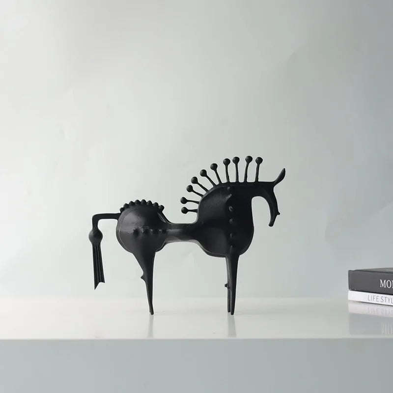 Black horse sculpture on a white surface with a light gray background, Obroi