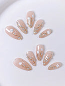 Set of beige nail art designs with floral and heart decorations on a white background, Obroi