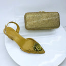 Gold studded shoe and matching clutch on a white background, Obroi