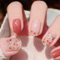 Close-up of a hand with pink nail polish and floral designs on a blurred background, Obroi