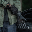 Person wearing black gloves and a green jacket with a blurred background, Obroi