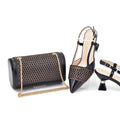 Black clutch bag with gold chain and black high-heeled shoes on a white background, Obroi