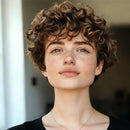 Woman with short, curly hair wearing a black top against a blurred indoor background, Obroi