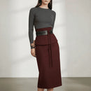 Woman wearing a gray sweater and brown skirt with a belt against a plain background, Obroi