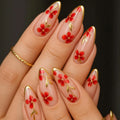 Nails with red floral design and gold accents on a dark background, Obroi